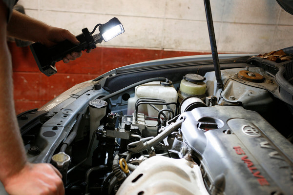 Mechanic using LED work light bz401-5 to look under car hood Mechanic using LED work light bz401-5 to look under car hood